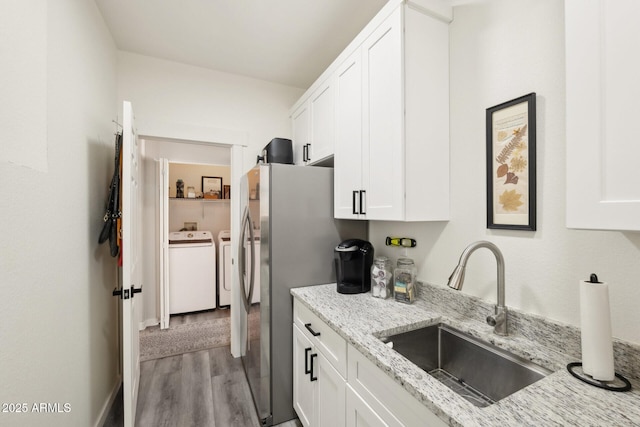 kitchen featuring sink, washer and clothes dryer, white cabinetry, and light stone countertops