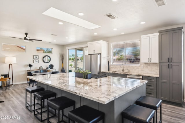 kitchen with white cabinets, a breakfast bar, appliances with stainless steel finishes, and a spacious island