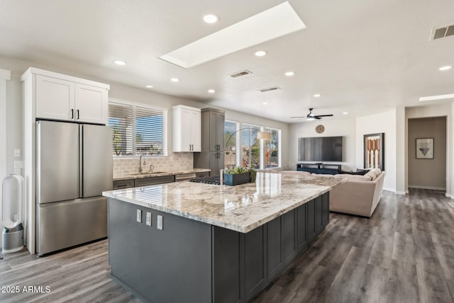 kitchen featuring stainless steel fridge, a large island, white cabinetry, ceiling fan, and sink