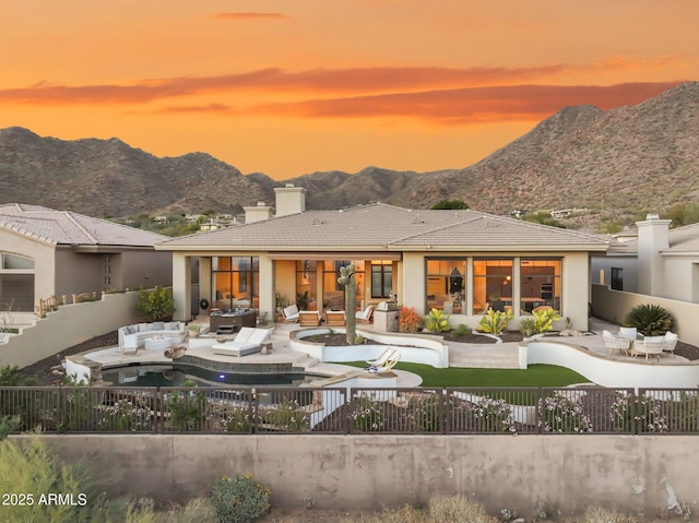 back house at dusk featuring a mountain view, a patio area, and outdoor lounge area