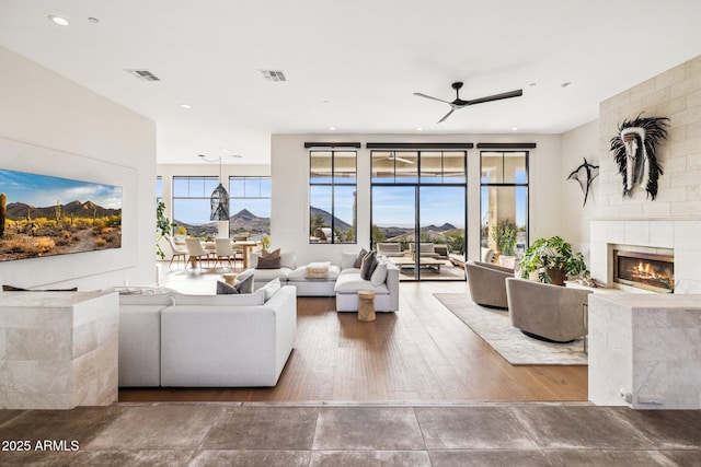 living room featuring a tiled fireplace, a mountain view, and ceiling fan