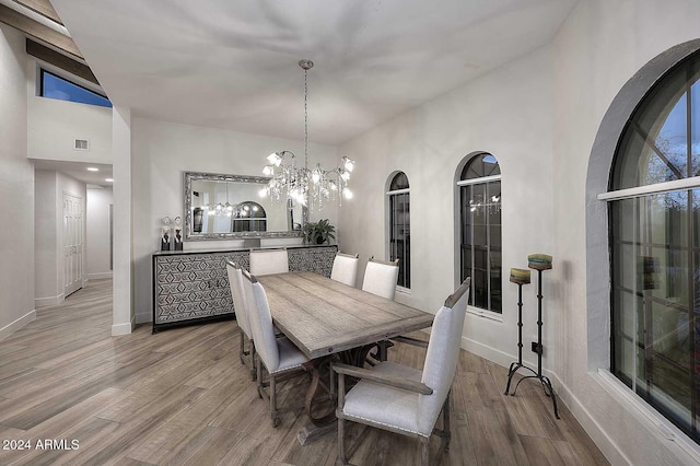 dining area featuring an inviting chandelier, high vaulted ceiling, and light hardwood / wood-style flooring