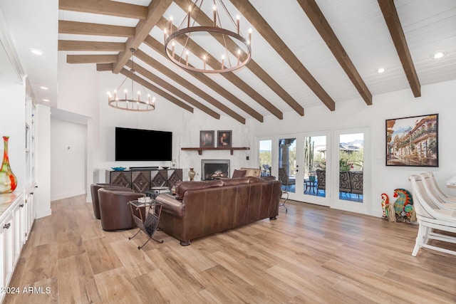 living room featuring high vaulted ceiling, light hardwood / wood-style flooring, beamed ceiling, a large fireplace, and a chandelier