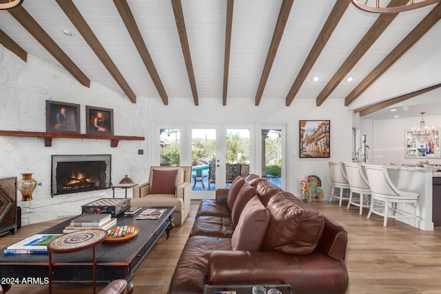 living room featuring french doors, an inviting chandelier, a stone fireplace, vaulted ceiling with beams, and wood-type flooring