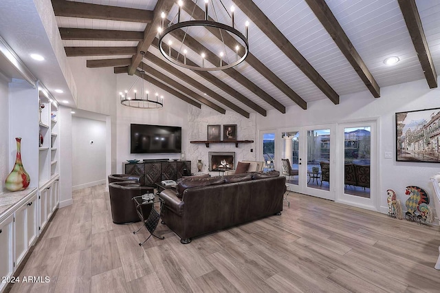 living room with beamed ceiling, light hardwood / wood-style floors, a fireplace, and an inviting chandelier