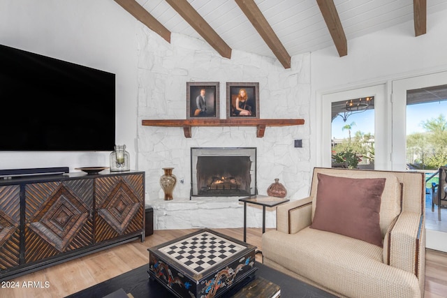 living room with a stone fireplace, hardwood / wood-style floors, beamed ceiling, and high vaulted ceiling