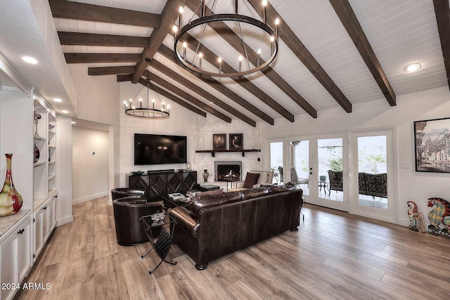 living room with beamed ceiling, a notable chandelier, a fireplace, and light hardwood / wood-style flooring