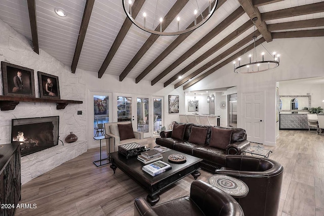 living room with high vaulted ceiling, a stone fireplace, beam ceiling, wood-type flooring, and a chandelier