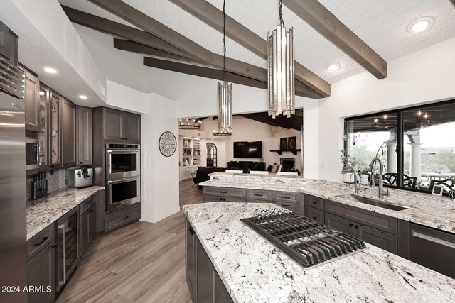 kitchen featuring light stone countertops, dark brown cabinetry, stainless steel appliances, sink, and light hardwood / wood-style flooring