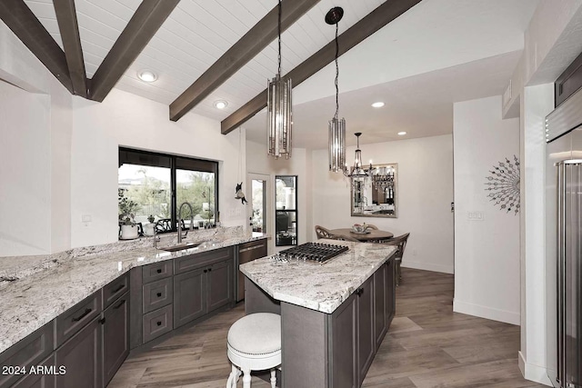 kitchen with hardwood / wood-style floors, vaulted ceiling with beams, light stone countertops, and decorative light fixtures