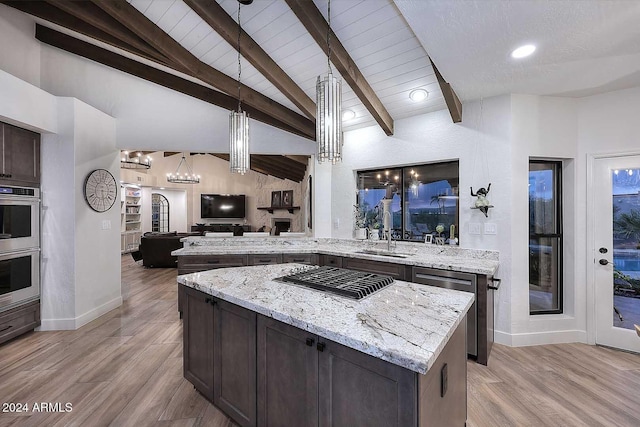 kitchen featuring light wood-type flooring, light stone counters, a kitchen island, and sink