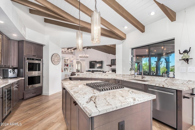 kitchen with light stone countertops, dark brown cabinets, stainless steel appliances, sink, and light hardwood / wood-style flooring