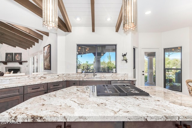 kitchen with sink, lofted ceiling with beams, dark brown cabinets, and stainless steel gas stovetop