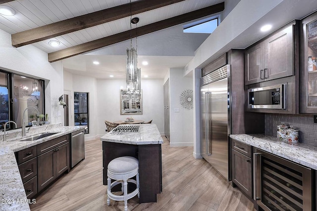 kitchen featuring light stone countertops, pendant lighting, built in appliances, light hardwood / wood-style floors, and wine cooler