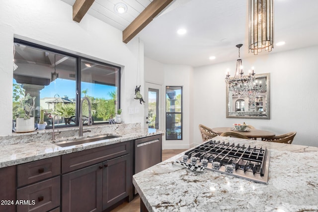 kitchen featuring an inviting chandelier, sink, light stone counters, dark brown cabinetry, and stainless steel appliances