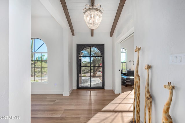 entrance foyer featuring vaulted ceiling with beams, light wood-type flooring, and an inviting chandelier