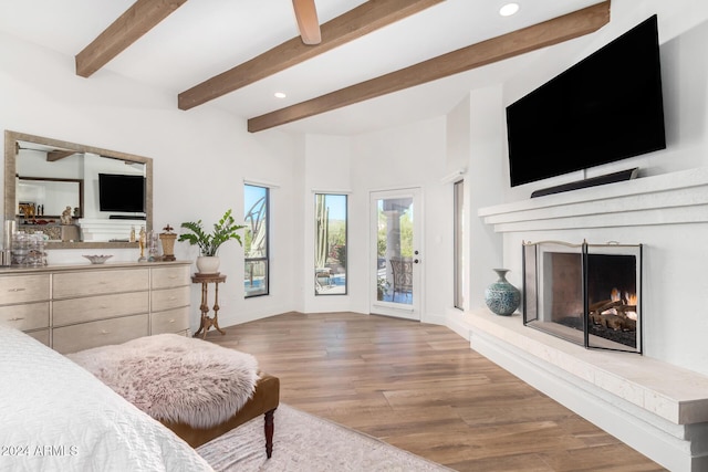 bedroom with access to exterior, light hardwood / wood-style floors, a brick fireplace, and beamed ceiling