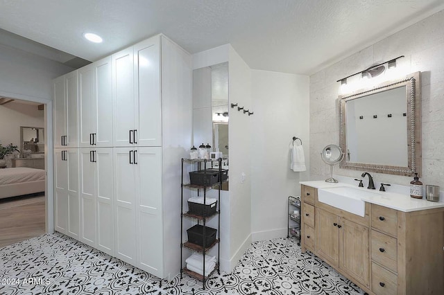 bathroom with a textured ceiling, vanity, and tile walls