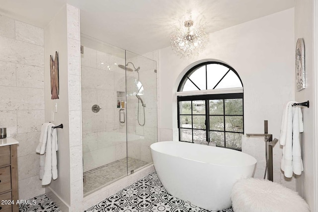 bathroom with tile patterned floors, vanity, independent shower and bath, and an inviting chandelier