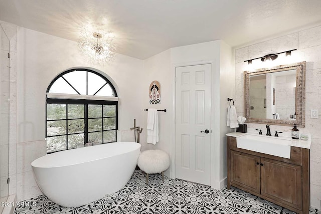 bathroom featuring tile patterned floors, a tub, vanity, and tile walls