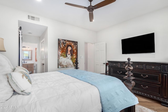 bedroom with ensuite bathroom, light hardwood / wood-style flooring, and ceiling fan