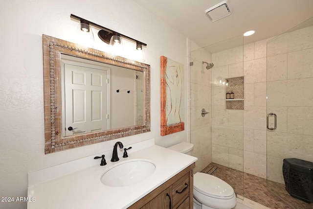 bathroom with vanity, a shower with shower door, and toilet