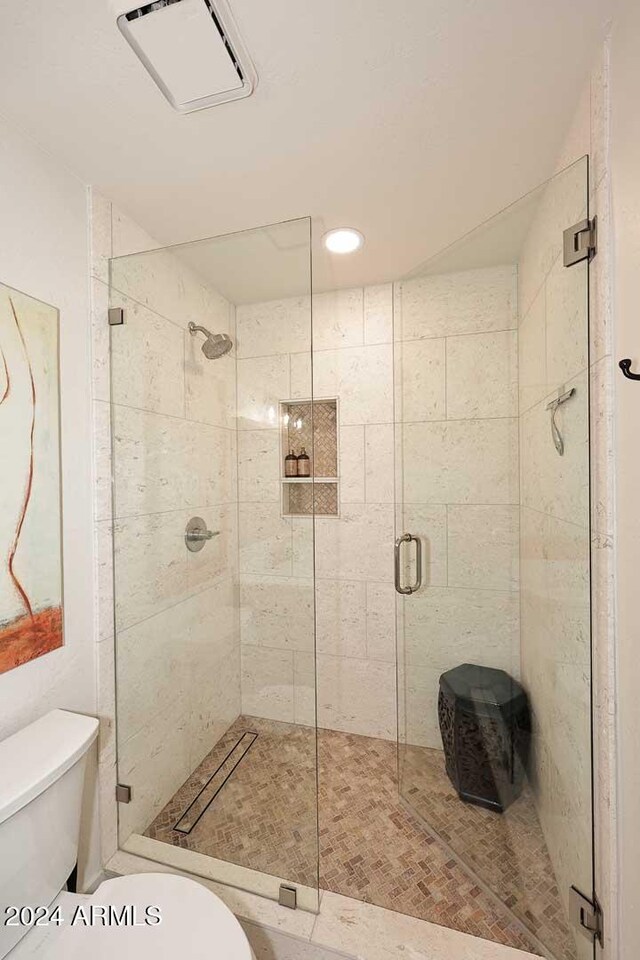 bathroom featuring toilet and a shower with door