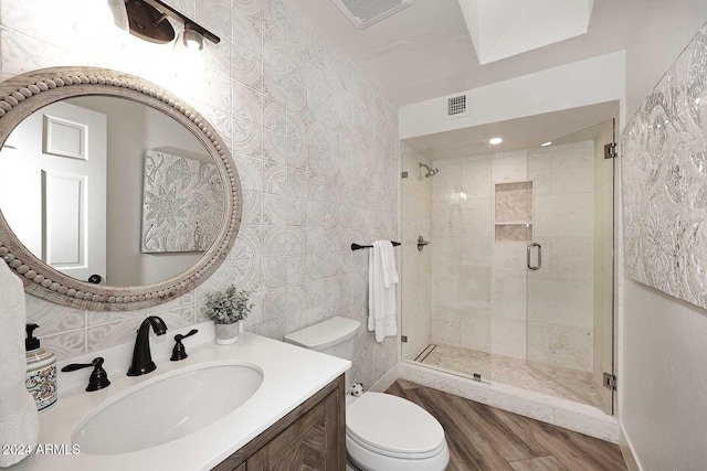 bathroom with vanity, hardwood / wood-style flooring, toilet, tile walls, and walk in shower