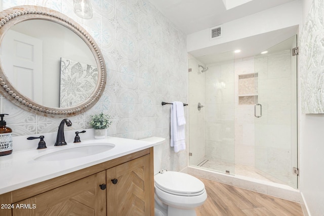 bathroom featuring an enclosed shower, vanity, tile walls, hardwood / wood-style floors, and toilet