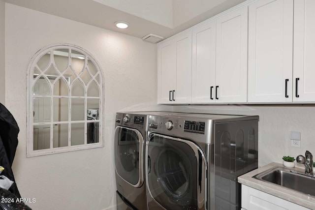 clothes washing area with cabinets, sink, and washing machine and clothes dryer