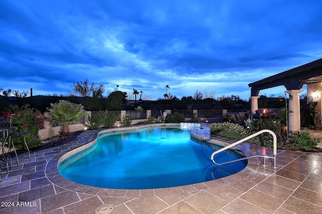 pool at dusk with a patio area