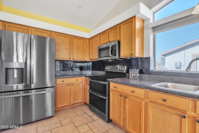 kitchen with lofted ceiling, sink, backsplash, and stainless steel appliances