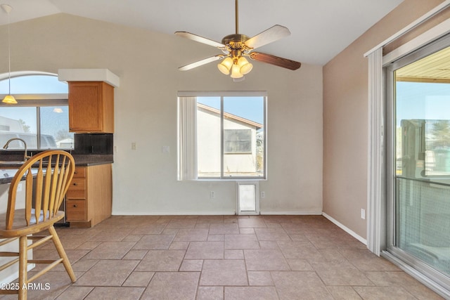 unfurnished dining area with vaulted ceiling, sink, and ceiling fan