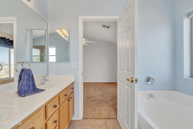 bathroom with tile patterned flooring, vanity, vaulted ceiling, and a bath