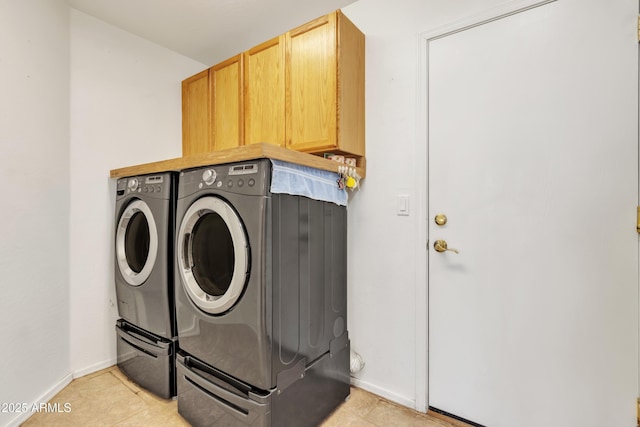 washroom featuring cabinets, light tile patterned floors, and washing machine and clothes dryer