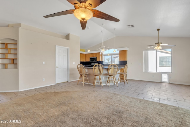 kitchen with a breakfast bar, vaulted ceiling, light carpet, kitchen peninsula, and ceiling fan