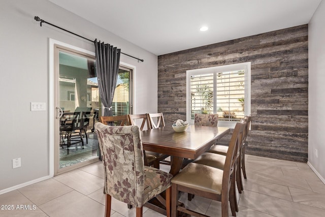 dining room with light tile patterned flooring, an accent wall, and baseboards