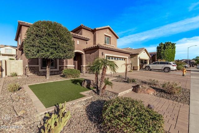 mediterranean / spanish home with a tile roof, concrete driveway, stone siding, and stucco siding