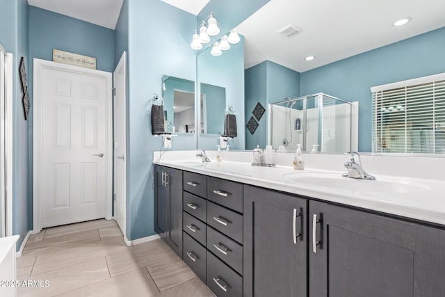 full bathroom featuring a sink, visible vents, double vanity, and a shower stall