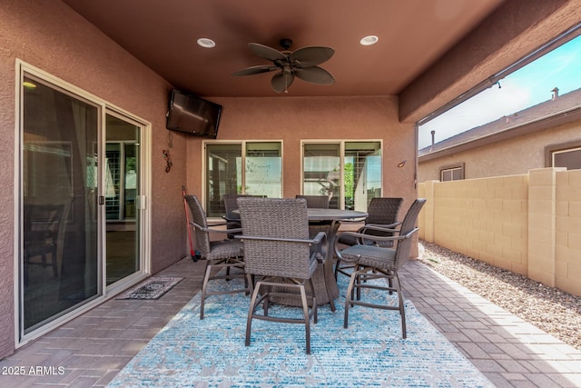 view of patio with outdoor dining space, a ceiling fan, and fence