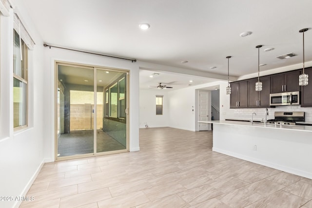 1081 E Armstrong Way, Chandler, AZ 85286 - kitchen featuring stainless steel appliances, dark brown cabinets, decorative backsplash, decorative light fixtures, and open floor plan