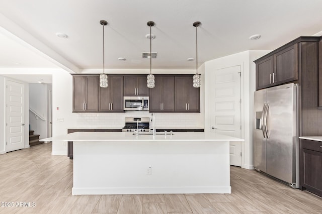 1081 E Armstrong Way, Chandler, AZ 85286 - kitchen featuring stainless steel appliances, dark brown cabinetry, tasteful backsplash, and light countertops