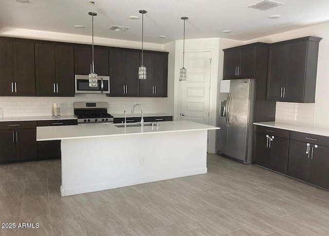 1081 E Armstrong Way, Chandler, AZ 85286 - kitchen featuring stainless steel appliances, a sink, backsplash, light countertops, and a center island with sink