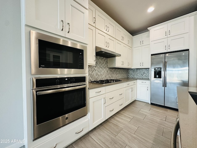 kitchen featuring tasteful backsplash, light stone counters, stainless steel appliances, and white cabinets