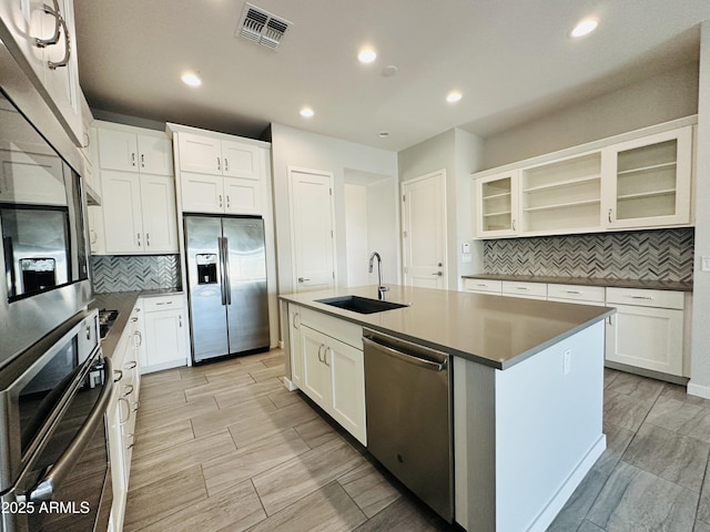 kitchen with appliances with stainless steel finishes, sink, a center island with sink, and white cabinets