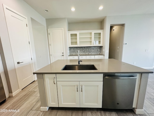 kitchen with sink, white cabinetry, stainless steel dishwasher, an island with sink, and backsplash