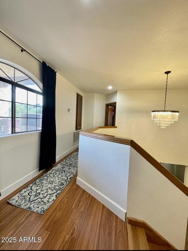 hallway with hardwood / wood-style flooring and an inviting chandelier