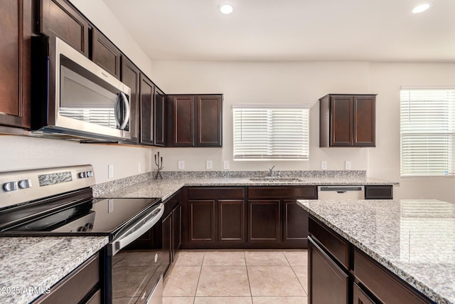 kitchen featuring sink, light stone countertops, dark brown cabinets, light tile patterned flooring, and stainless steel appliances