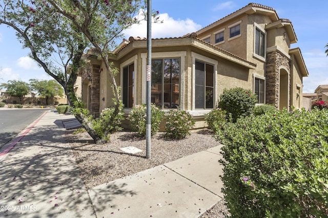 view of home's exterior featuring stucco siding, a tiled roof, and stone siding