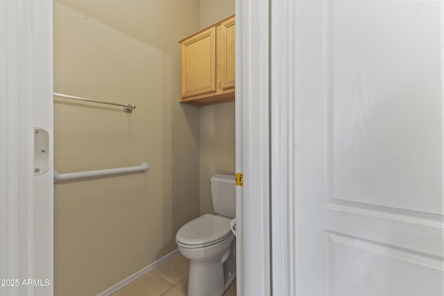 bathroom with toilet, baseboards, and tile patterned flooring